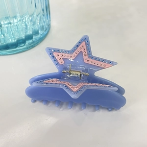 Detail of star-shaped hair claw clip with celestial blue glitter and pink rhinestones