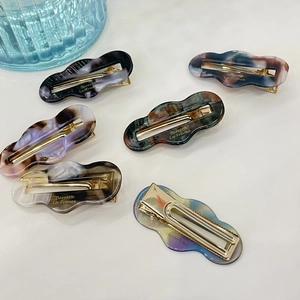 Close-up of six irregular hollow resin hair clips with marble patterns and metal clips