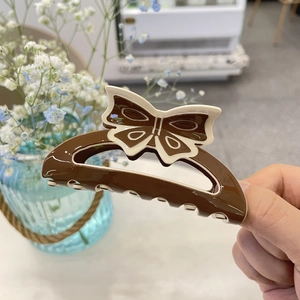 Close-up of a large brown and cream acrylic butterfly hair claw clip with smooth resin finish