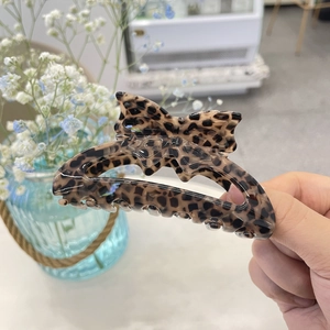 Detailed view of large acrylic leopard print bow hair claw clip with smooth polished finish