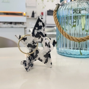Star-shaped acrylic hair claw with black and white marble pattern and gold ring detail