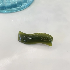 Close-up of wavy green resin hair clip featuring gold SANSHINE Handmade lettering