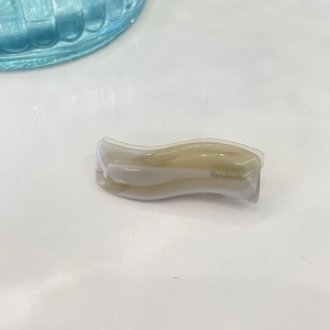 Close-up of a wavy marble pattern hair clip with gold SANSHINE Handmade text detail