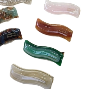 Set of wavy acetate hair clips in multiple colors with glossy finish and brand logo