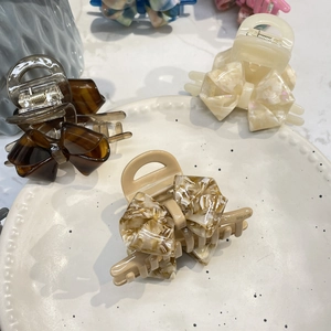 Detailed close-up of premium acetate hair claws with elegant double-layered bow designs