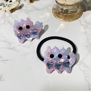 Detail of pink marble acetate cat hair clip and elastic tie with heart rhinestones