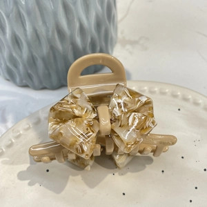 Elegant acetate hair claw clip with amber marble bow design and cream base finish