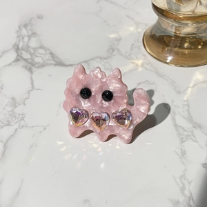 Close-up of pink acetate cat hair clip with iridescent heart-shaped rhinestones detail