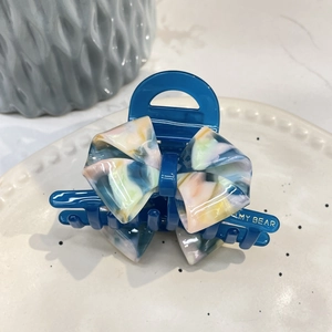 Close-up of acetic acid hair claw with colorful marble butterfly knot on a ceramic tray