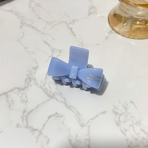 Close-up of light blue acetate bow hair claw with Barrette la France gold lettering