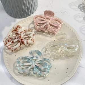 Detailed set of four colorful acetate butterfly hair claws on a ceramic display tray
