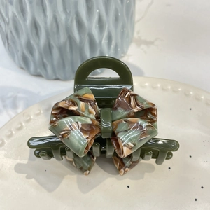 Detail of elegant dark green acetate hair claw clip with a marble butterfly pattern design