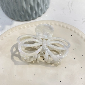 Detailed macro shot of a cream white acetate butterfly hair claw clip on a ceramic plate