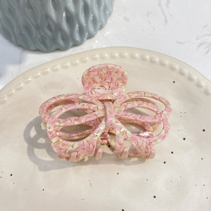 Detail of pink marble acetate butterfly hair claw clip on a ceramic tray display