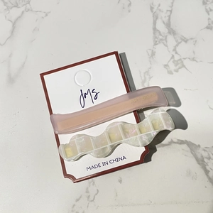 Pink matte and glitter wavy hair clips set on brand card over marble background