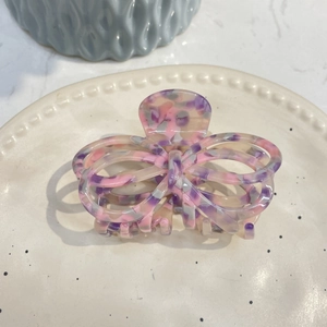 Detail of hollow butterfly hair claw with purple and cream marble pattern on ceramic plate