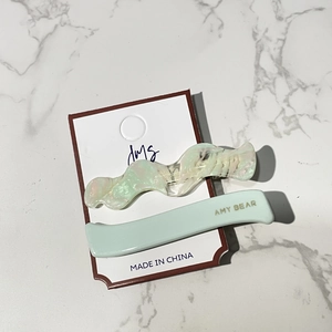 Candy colored wavy acetate hair clips with mint green matte finish and gold lettering