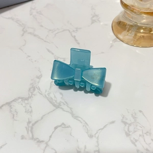 Detailed macro view of light blue pearlescent acetate bow hair clip on marble background