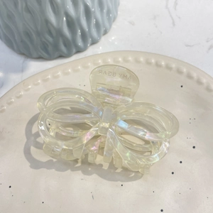 Iridescent butterfly hair claw clip in acetate material on a decorative beige plate