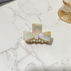 Detail of a mosaic marble acetate bow hair claw clip with gold Barrette La France lettering