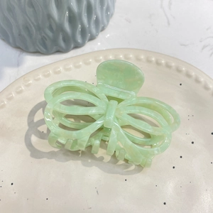 Detail of mint green acetate butterfly hair claw with hollow lines on ceramic tray