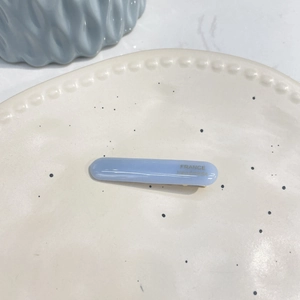 Detail of light blue acetate hair clip with gold France Handmade lettering on ceramic plate