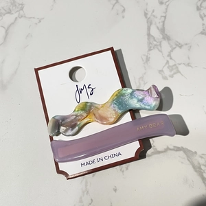 Close-up of wavy pearlescent and purple matte hair clips on original white card