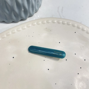 Detailed macro view of acetate blue hair clip with gold France Handmade logo text