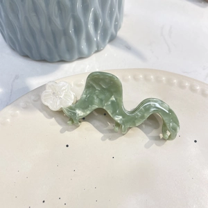 Elegant green marble acetate flower hair claw clip with floral detail on ceramic plate