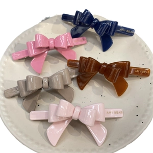 Five candy-colored acetate bow hair clips in a ceramic tray for sweet girls' styling