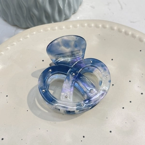 Blue marble acetic acid pretzel hair claw with silver studs on elegant ceramic dish