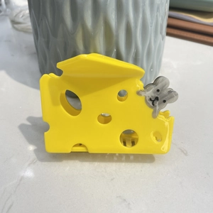 Vue détaillée de la pince à cheveux fromage jaune avec petite souris 3D sur marbre