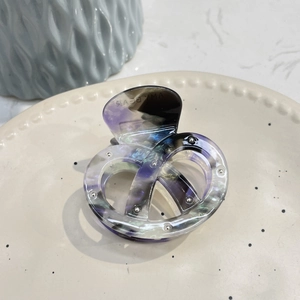 Close-up of marble acetate hair claw clip with silver dots on a ceramic plate