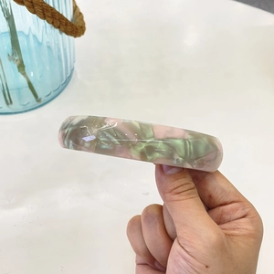 Dettaglio molletta in acetato con trama marmorizzata rosa e verde menta elegante