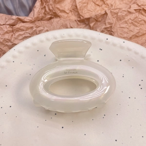 Detailed shot of cream white acetate hair claw with pearlescent finish and French text