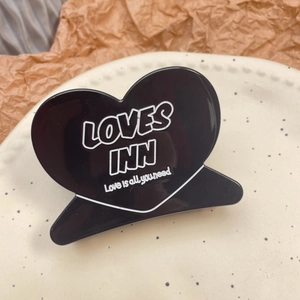 Pince à cheveux noire brillante en forme de cœur avec texte blanc sur assiette décorative
