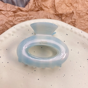 Elegant light blue acetate hair claw with iridescent finish and gold lettering