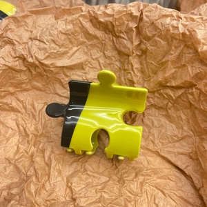 Detail of yellow and black jigsaw puzzle hair claw clip with glossy finish and jagged teeth