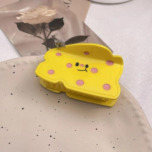 Detail einer gelben Käse Haarklammer mit Smiley Gesicht und kleiner Katzenfigur