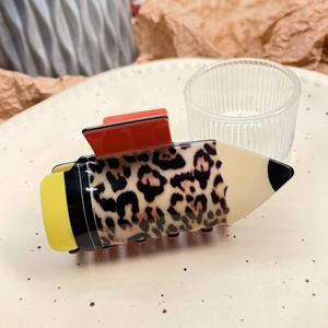 Macro shot of a leopard print pencil hair claw clip on a stylish ceramic plate