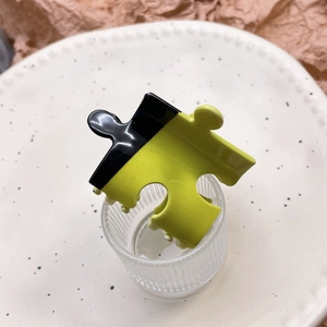 Detail view of puzzle-shaped hair claw clip in neon yellow and black colors
