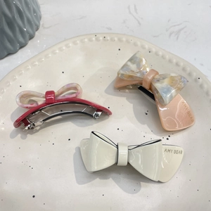 Vue détaillée des barrettes en acétate avec motifs marbrés et crème sur un plateau céramique