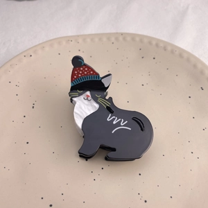 Pince à cheveux chat noir mignonne avec bonnet d'hiver et texture marbre sur plateau