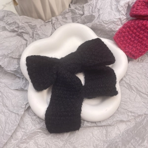 Détail d'une barrette à cheveux nœud en tricot noir sur un plateau en céramique
