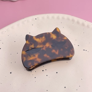 Close-up of tortoise shell cat hair claw clip on a decorative ceramic plate