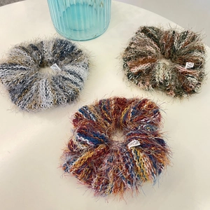 Close-up of three handmade mohair hair scrunchies with soft fluffy texture and colorful patterns