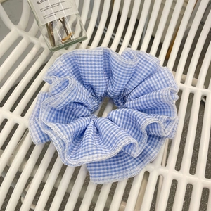 Detailed view of the blue and white checkered plaid fabric scrunchie with ruffled edges