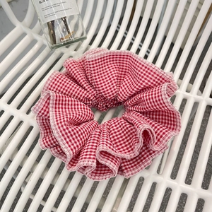Classic red and white plaid scrunchie with layered pleats on white fence background
