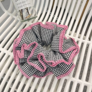 Detail of checkered scrunchie with pink scalloped edges and sweet pleated fabric texture