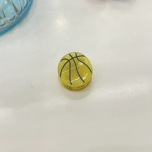 Detalle de pinza para el pelo con forma de baloncesto amarillo y líneas negras de acetato